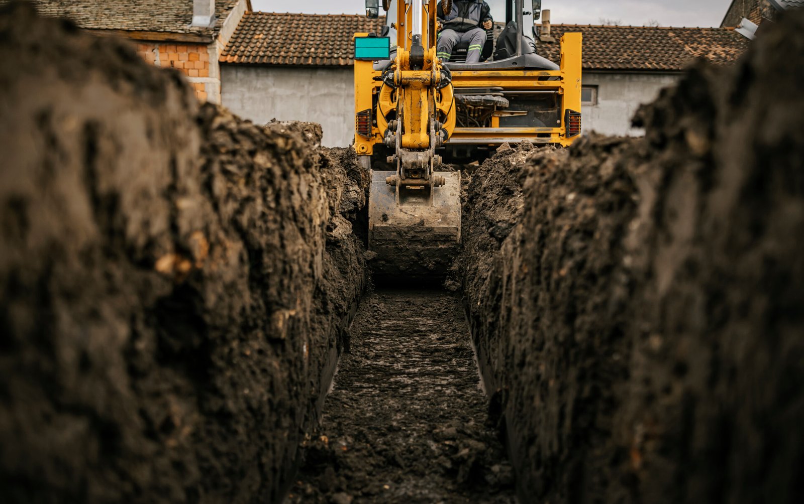 Cropped picture of a backhoe digging soil and making foundation at construction site.
